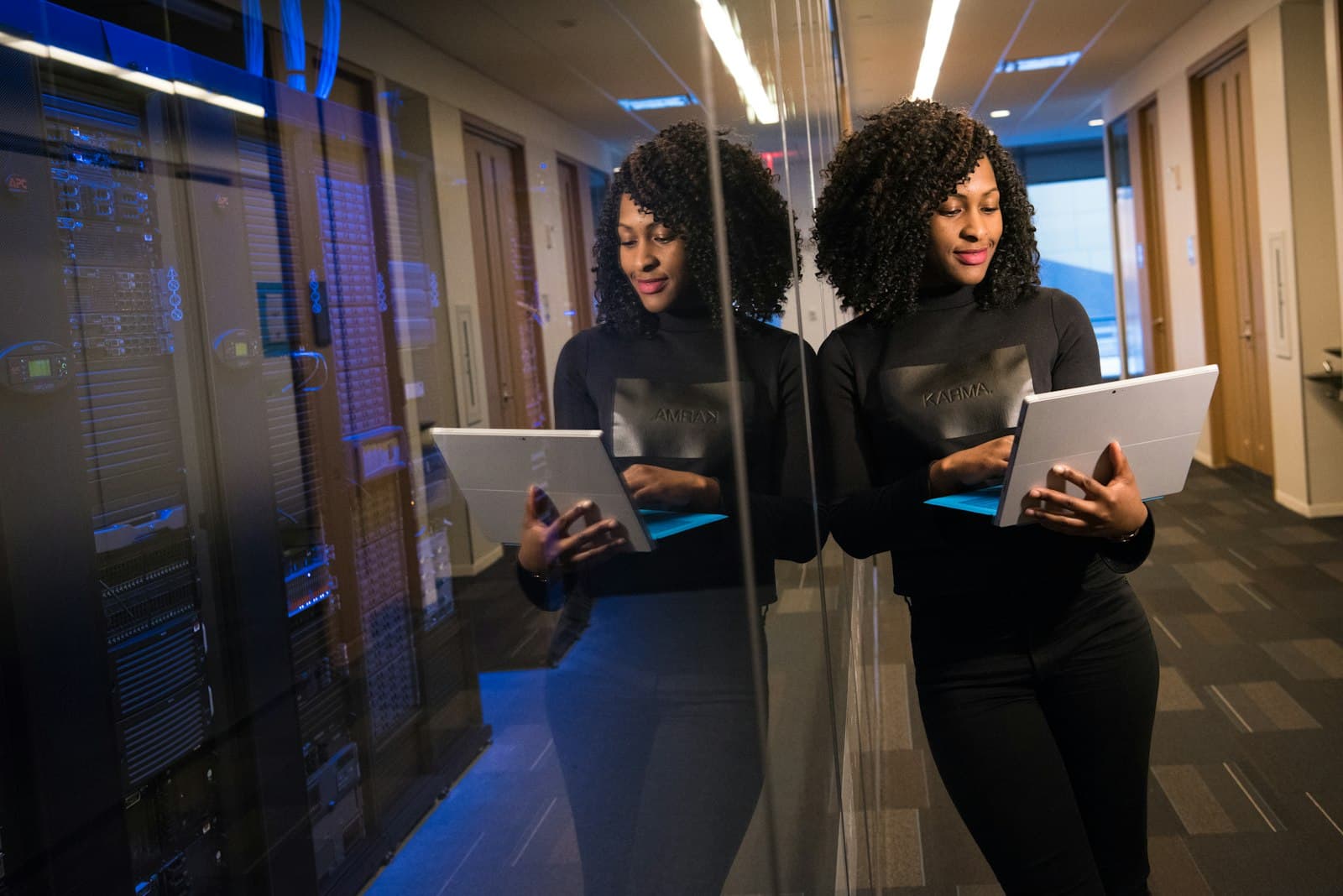 Engineer with a tablet walking a data centre aisle lined with lit server racks